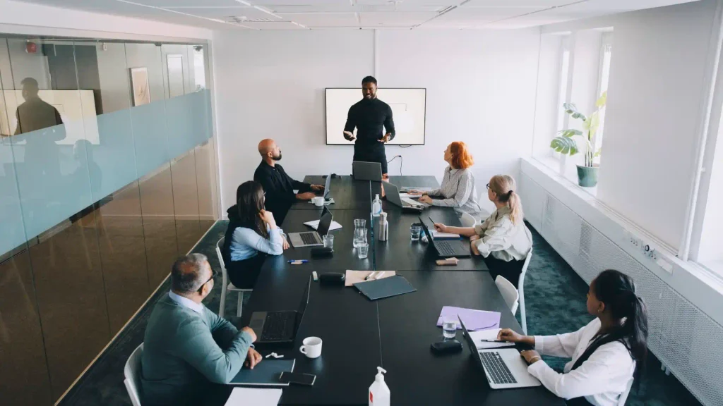 A team reviewing a brand identity design presentation on a conference room screen.